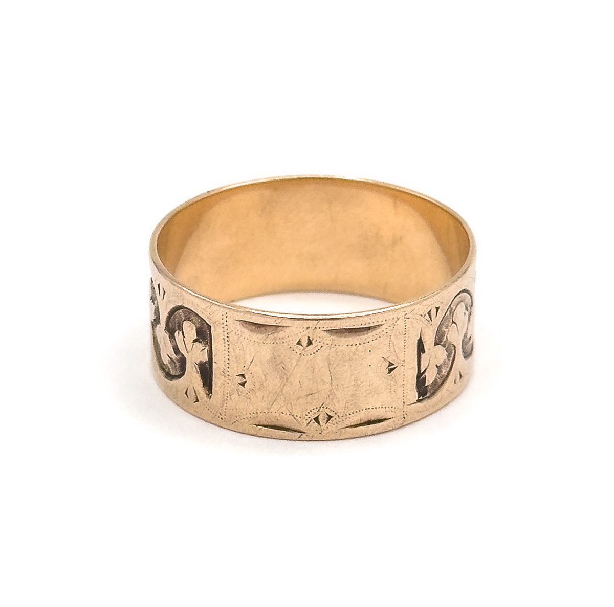 Straight-on front view with the small engraved cartouche panel centred on the wide band, a trefoil motif curving away at each side and the smooth inner shank visible above.
