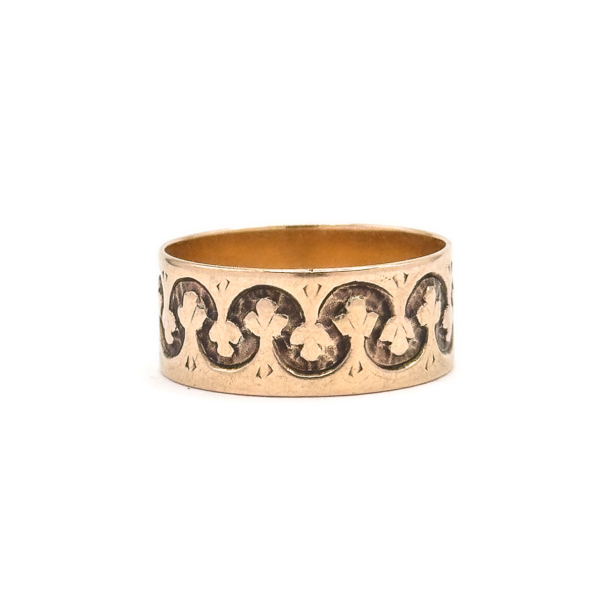 Upright view with the cartouche turned out of sight, so an unbroken run of linked trefoils fills the whole width of the wide rose gold band, the inner shank showing as a narrow oval above.