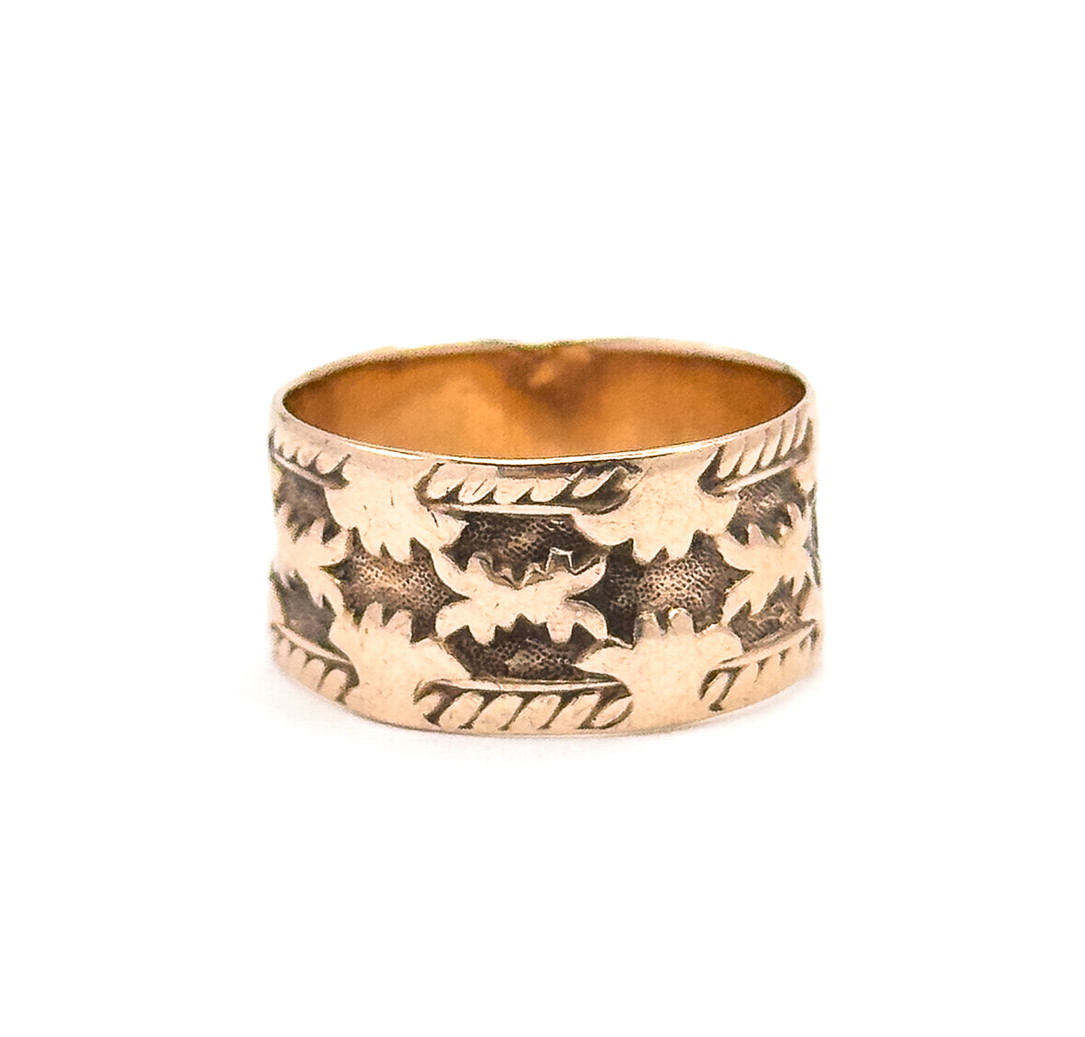 Tipped just enough to catch the smooth bright interior wall inside the rim, contrasting with the carved leaf row and rope borders on the outside of the low-profile band.