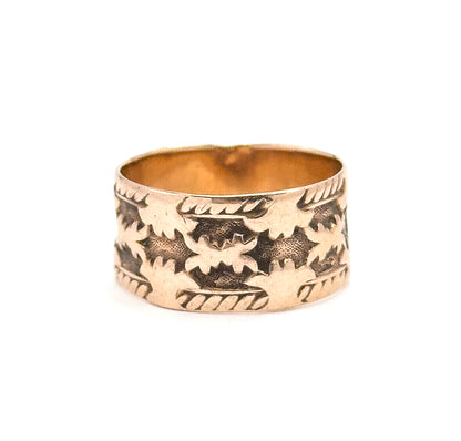 Tipped just enough to catch the smooth bright interior wall inside the rim, contrasting with the carved leaf row and rope borders on the outside of the low-profile band.