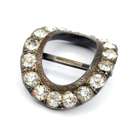Angled view on a plain white background, the patinated silver frame tilted so the hand-etched border inside the oval and the straight central bar are clearly visible.