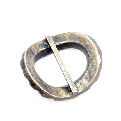The reverse of the buckle, showing the plain patinated underside of the oval frame and the flat central bar seated in its notches at each side.