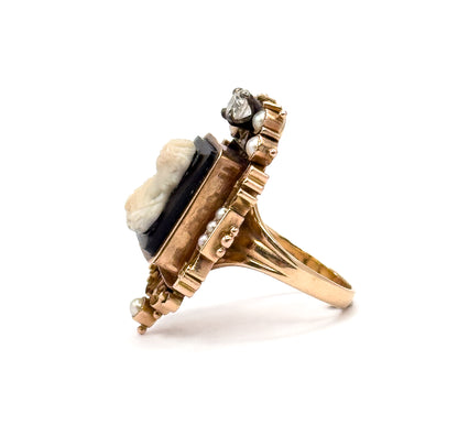 Side profile against white showing how high the setting stands above the tapering rose gold shank, the cameo's black ground seen edge-on with pearls stepping down the frame.
