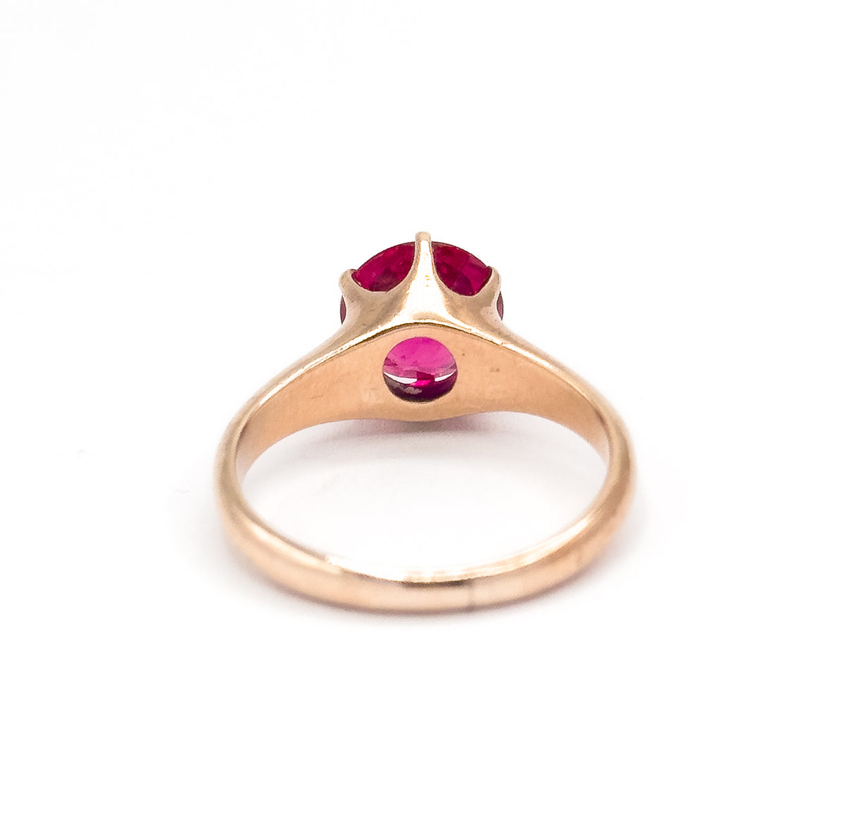 Rear view with the rose gold shank standing upright, showing the open underside of the setting where the bright pink stone shows through a round window below the prongs.