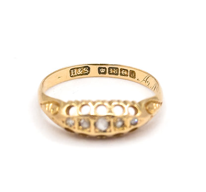 Upright view through the band opening with the row of stamped punches and script engraving legible across the inner shank, and all five round diamonds visible below in the pierced gallery.