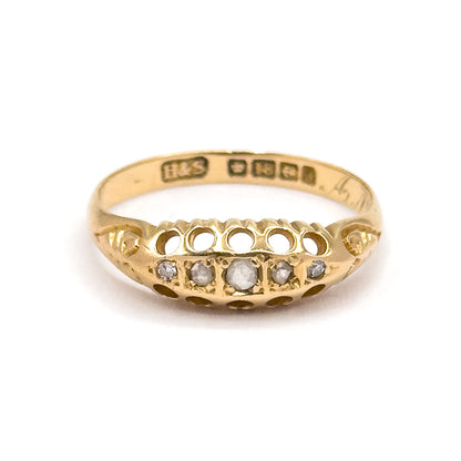 Standing upright face-on with the band's far inner wall and its row of punches visible through the opening, the five graduated diamonds lined up below in a gallery of pierced round arches.