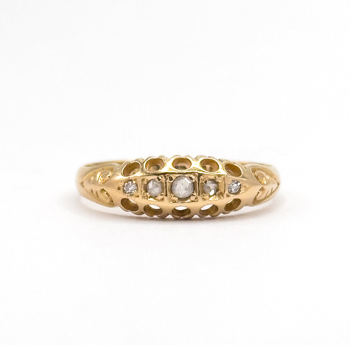 Small in the frame against plain white, the whole ring stands upright so its low domed face reads clearly, the centre diamond largest and the stones stepping down in size to each end.