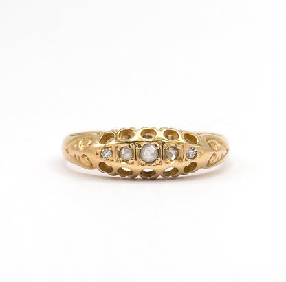 Small in the frame against plain white, the whole ring stands upright so its low domed face reads clearly, the centre diamond largest and the stones stepping down in size to each end.