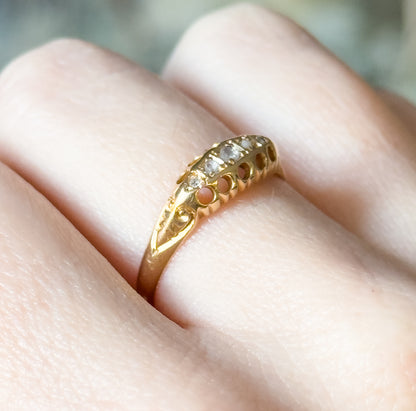 Angled side view on the finger, showing the row of pierced arches along the gallery and the engraved shoulder flowing down into the narrow shank.