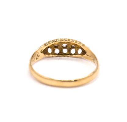 Rear view of the setting's underside, where five round openings in the yellow gold gallery show the backs of the diamonds, with script engraving curving along the inner shank beneath.