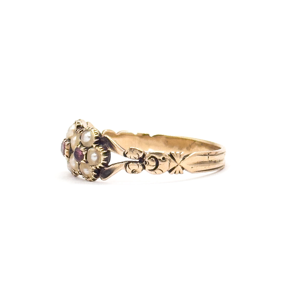 Profile view from the left, the crimped collets of the seed pearls and one tourmaline visible in silhouette as the carved leaf shoulder and floral motif run back along the shank.