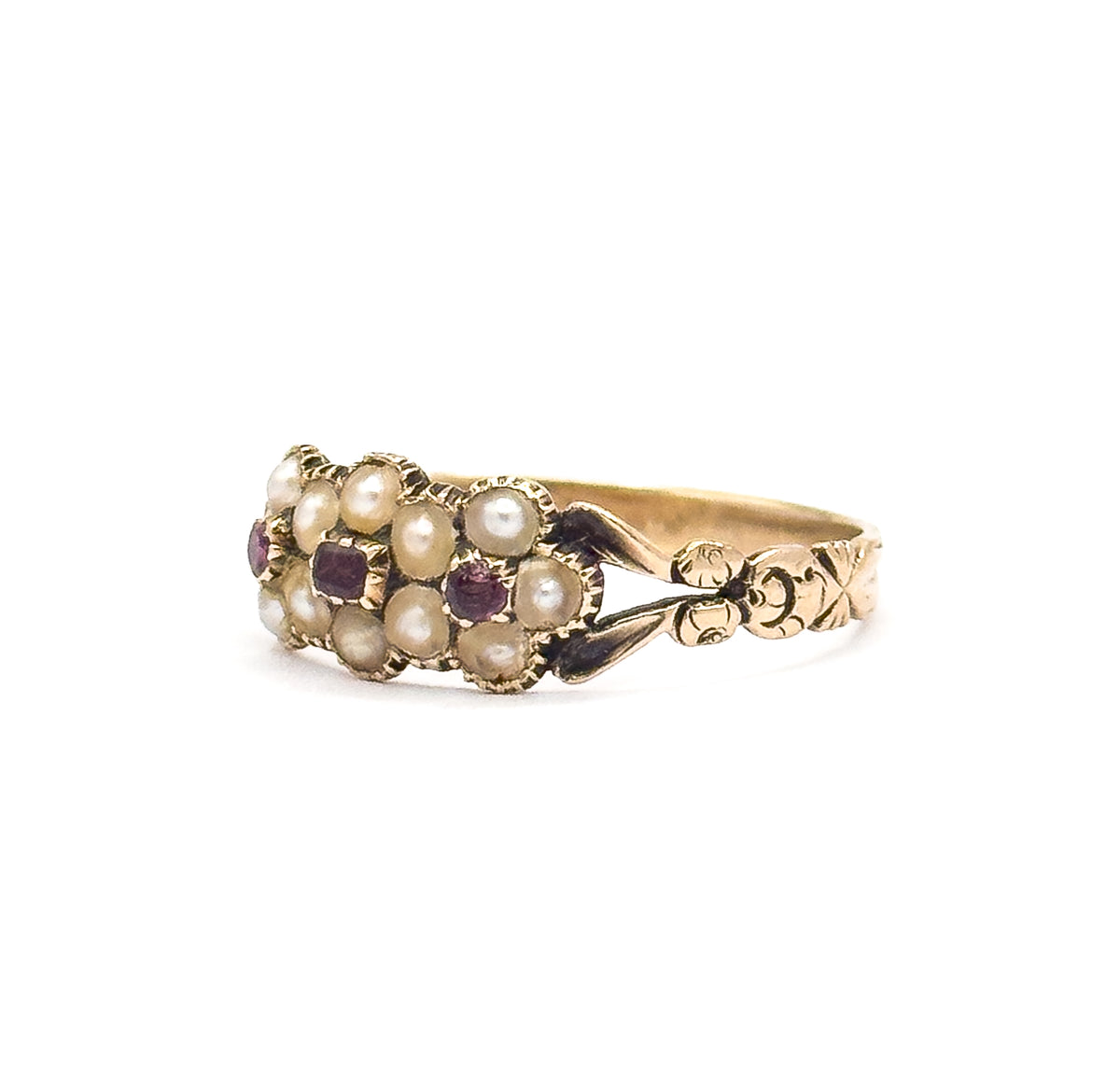 Angled profile from the right, the pearl flowers and both pinkish-purple tourmalines tilted toward the viewer while the carved leaf shoulder and floral motif run away along the shank.
