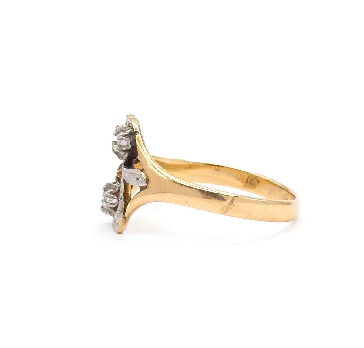 Side profile against white, showing how low the "S" face sits above the finger as the yellow gold shank sweeps up to the prong-set diamonds in their white gold settings.