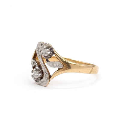 Almost the same view with slightly different angle, from the other side, showing the yellow gold shank splitting into two slender arms that frame an open gap beneath the diamond-set "S" face.