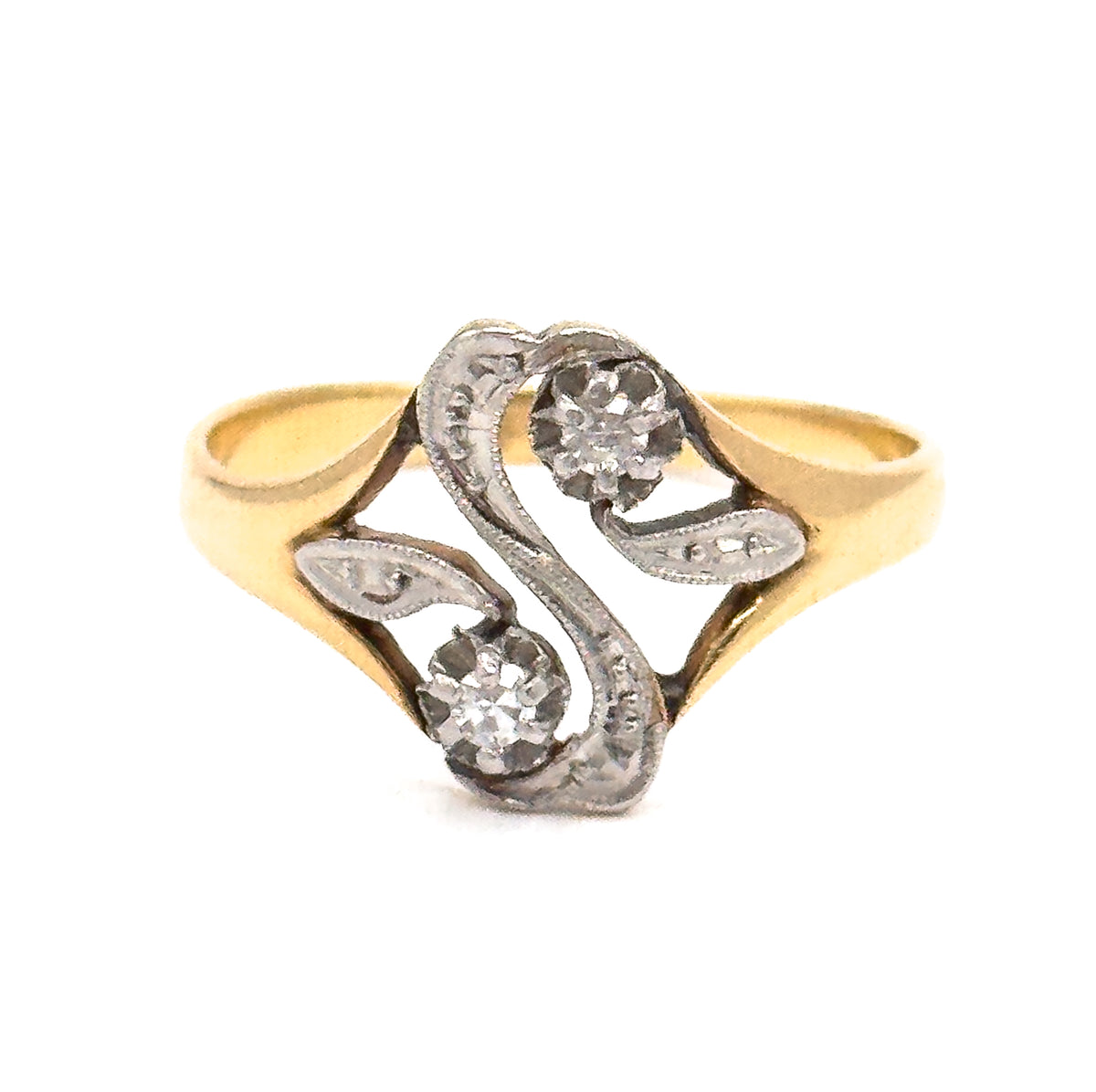 Almost the same view with slightly different angle, closer in so the two leaf-shaped openwork scrolls flanking the "S" read clearly, each tipped with a tiny milgrain-edged pierced eye.