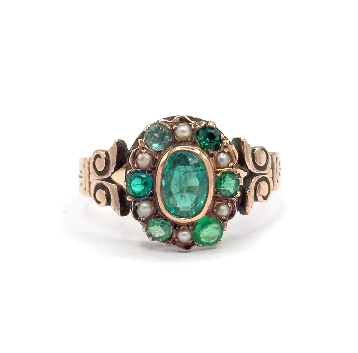 Close-up head-on of the face filling the frame, where each small green stone sits in its own prong setting between the round seed pearls, the gold bezel collar bright around the central oval.