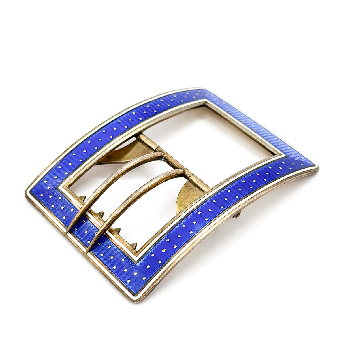 The whole rectangular buckle seen at an angle, its curved blue enamel frame with white edging surrounding the open centre where the arched bars and prongs sit.