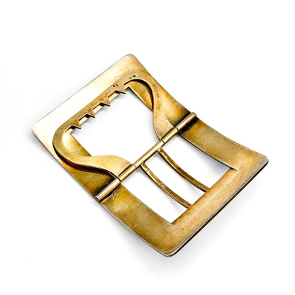 Flat-on view of the gold-washed silver reverse laid corner-to-corner, showing the broad hinged tongue plate ribbed with parallel grooves as it spans the opening to the notched bar.