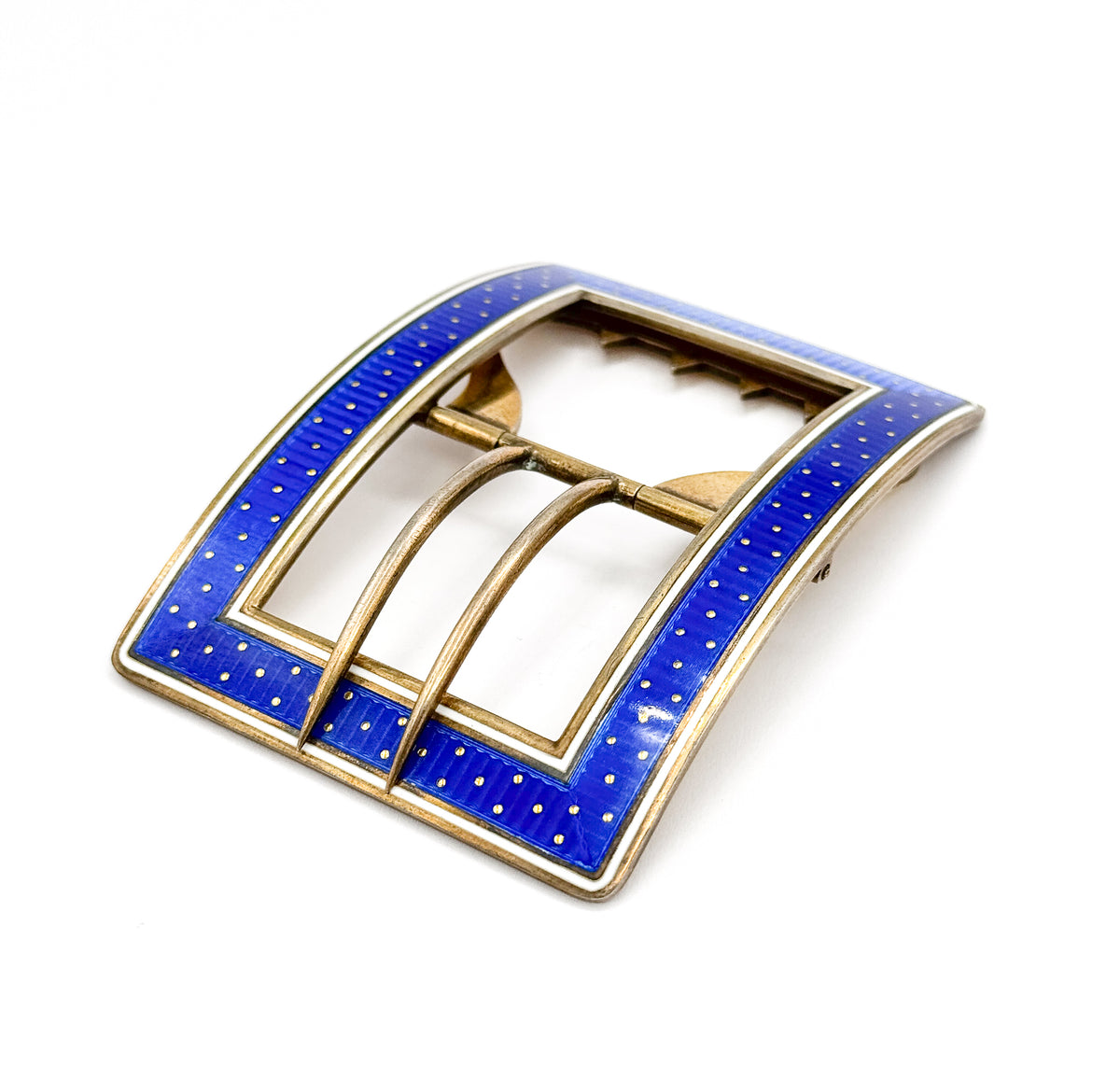 Angled view of the enamelled face at last, the deep blue guilloché field dotted with tiny gold points inside a crisp white border, with the slim tongue arching across the open centre.