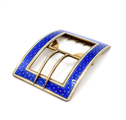 Angled view of the enamelled face at last, the deep blue guilloché field dotted with tiny gold points inside a crisp white border, with the slim tongue arching across the open centre.