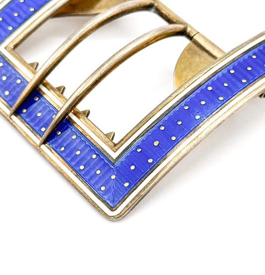 Edwardian blue guilloché enamel buckle in sterling silver with gold wash, shown in close-up on white, its corner band of blue enamel with gold dots and white edge meeting the arched inner bars.