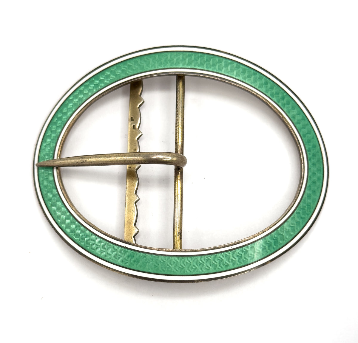 Straight-on flat view of the full oval from behind, showing the scalloped upright bar beside the plain straight bar and the prong lying across them, inside the mint green and white enamel rim.