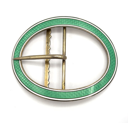 Straight-on flat view of the full oval from behind, showing the scalloped upright bar beside the plain straight bar and the prong lying across them, inside the mint green and white enamel rim.