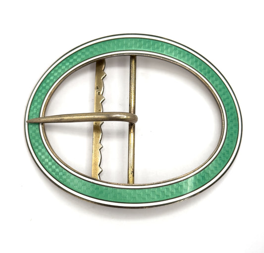 Straight-on flat view of the full oval from behind, showing the scalloped upright bar beside the plain straight bar and the prong lying across them, inside the mint green and white enamel rim.