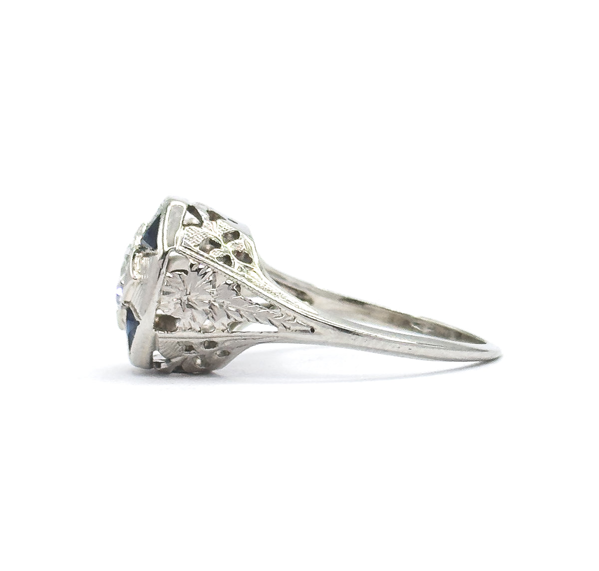 Side profile on white, showing how high the setting stands above the finger, with pierced and etched filigree shoulders tapering down to the slim shank.