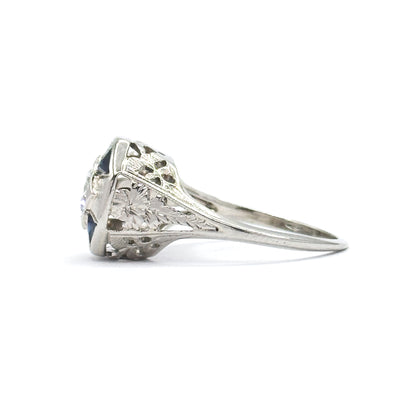 Side profile on white, showing how high the setting stands above the finger, with pierced and etched filigree shoulders tapering down to the slim shank.