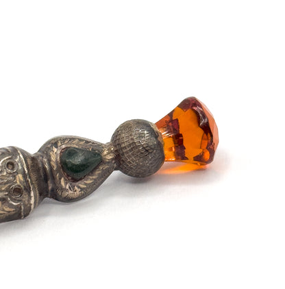 Close crop on the thistle head, with the faceted orange glass catching light above the cross-hatched sterling silver bulb and a teardrop of agate inlay in the engraved body below.