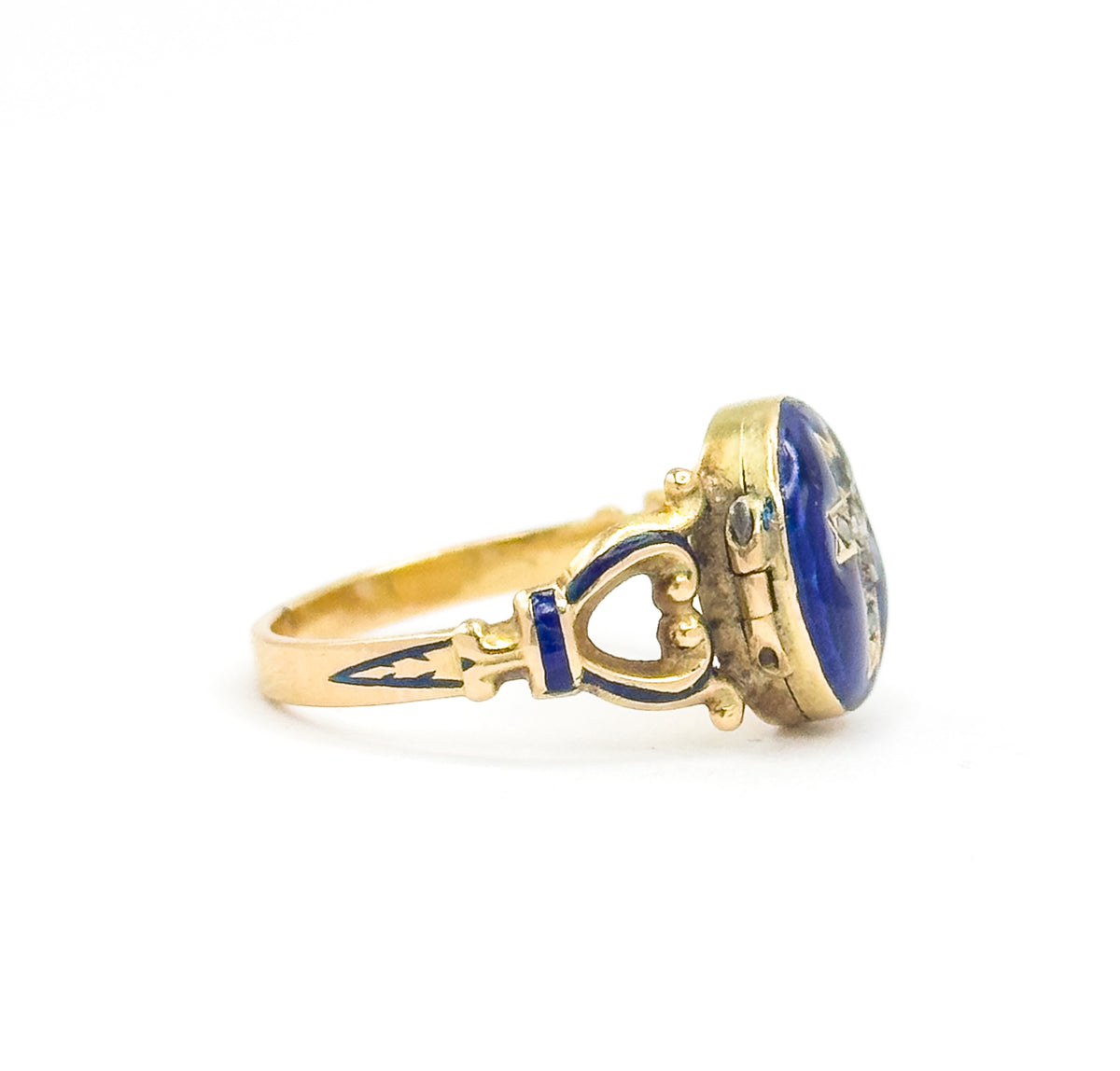 Side profile with the locket closed, showing the depth of the hinged case and its small hinge at the left, the heart-shaped openwork shoulder and blue enamel band leading to the slim shank.