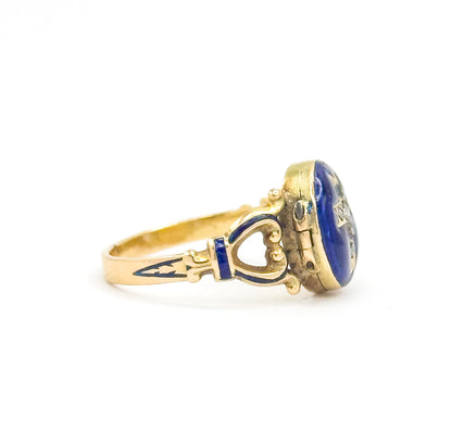 Side profile with the locket closed, showing the depth of the hinged case and its small hinge at the left, the heart-shaped openwork shoulder and blue enamel band leading to the slim shank.