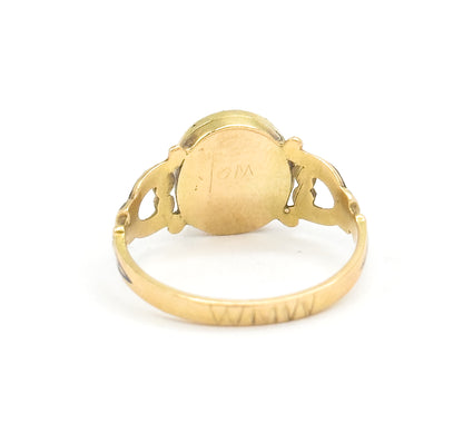 Rear view with the ring standing upright, showing the plain back of the locket case with its small engraving, the pierced shoulders either side and the inside of the shank below.