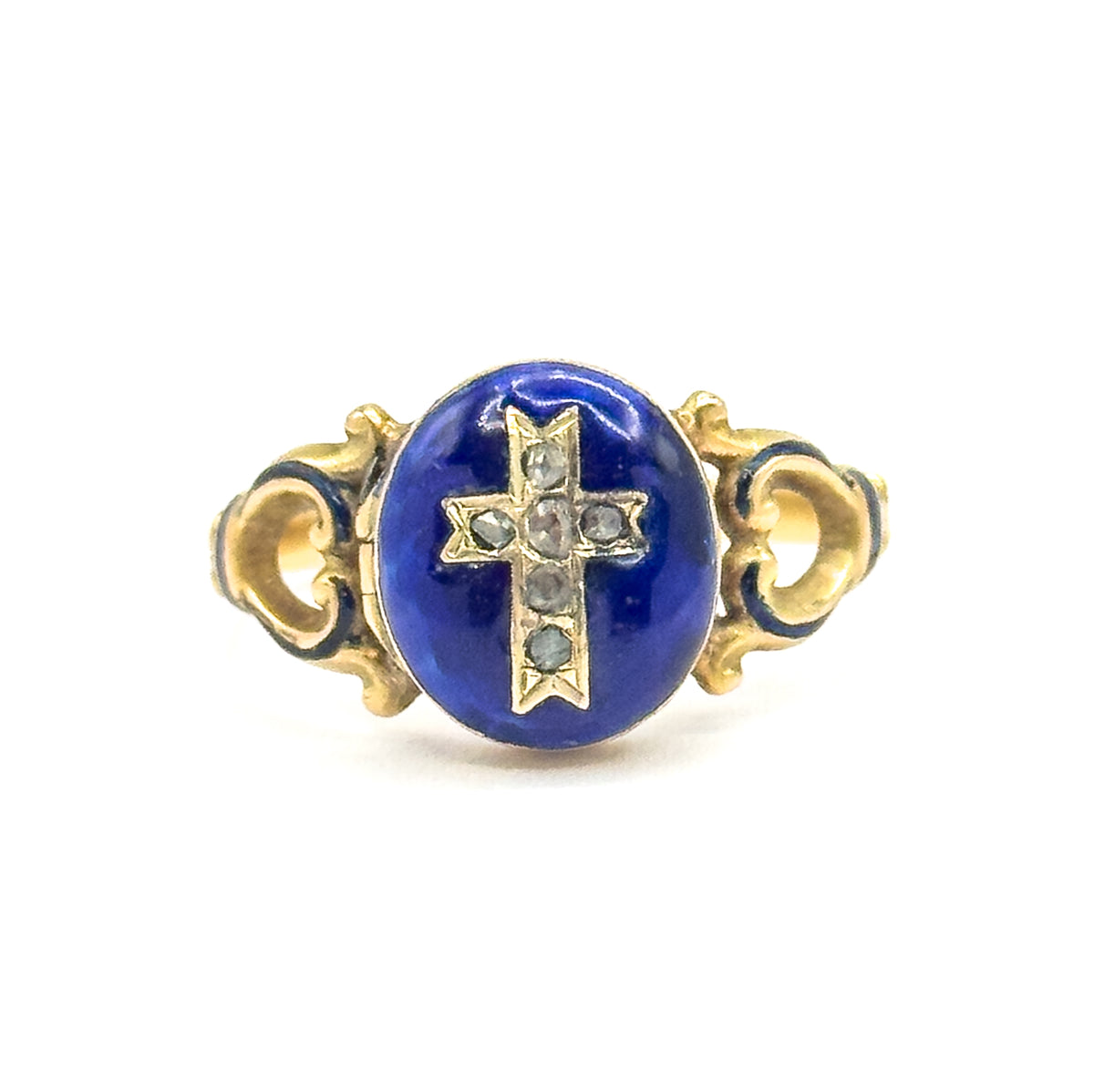 Close crop of the oval blue enamel face filling the frame, the six small faceted stones in its cross clearly spaced along the arms, with the locket case's hinge seam at the left edge.