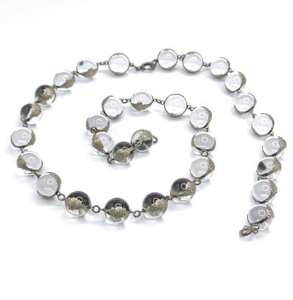 The whole strand coiled into a loose spiral on white, both sterling silver clasps visible at opposite ends, letting the full run of 32 orbs in floral mountings be counted in one view.
