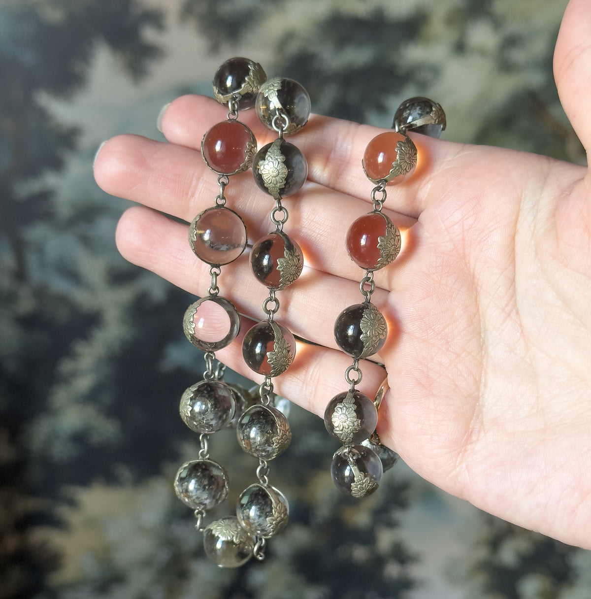 Coiled in an open palm, which gives a sense of scale — each clear orb in its floral silver mounting sits about as wide as a fingertip, linked in rows across the fingers.