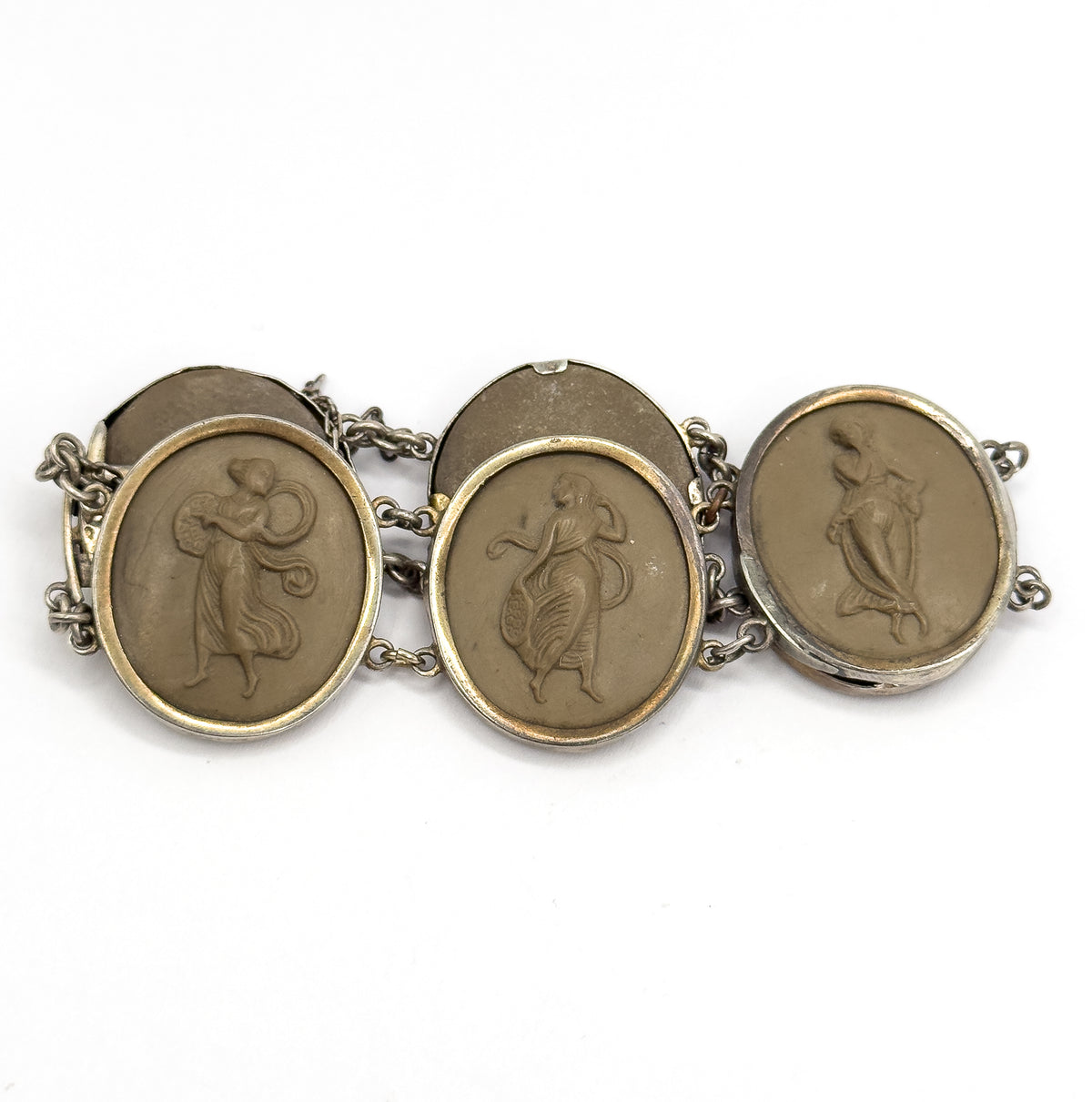 Tight crop filling the frame with three carved khaki-brown figures facing up and two blank cameo backs tipping away behind them, the gold-toned bezel rims and connecting links catching the light.