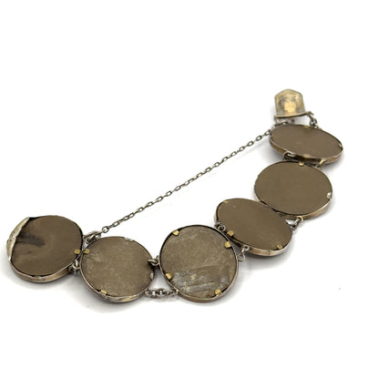Full reverse of the whole bracelet laid in an arc on a plain background, six flat cameo backs in their bezels with the hidden box clasp at one end and the safety chain spanning across.