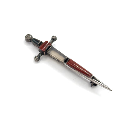 Angled from the point end on white, the reddish-brown and pale grey blade cabochons catching the light while the beaded crossguard and pommel recede behind.