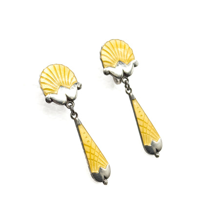 Both earrings lie angled on a plain white background, a close overhead view showing the fluted shell tops, the small chain links and the ribbed lemon enamel drops.