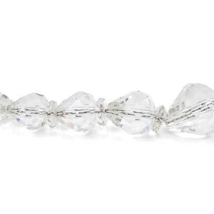 Extreme close-up of a few beads against white, the faceted colourless shapes alternating with small flat disc beads and the stringing cord visible running through each drilled hole.