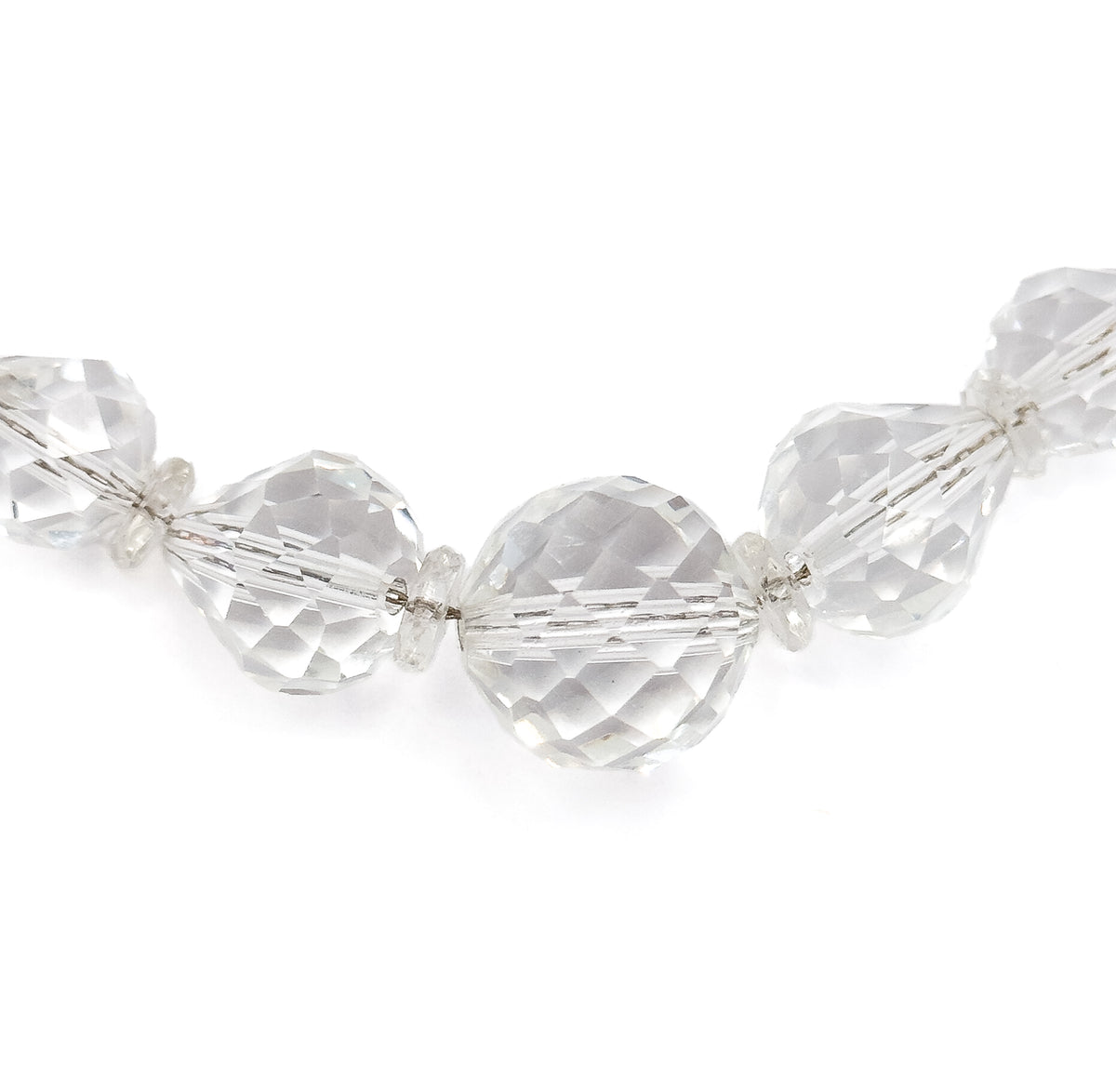 A straight-on view of the necklace's lowest arc, the big round centre bead flanked by flattened and cone-shaped faceted beads with tiny disc spacers between, all evenly lit against white.
