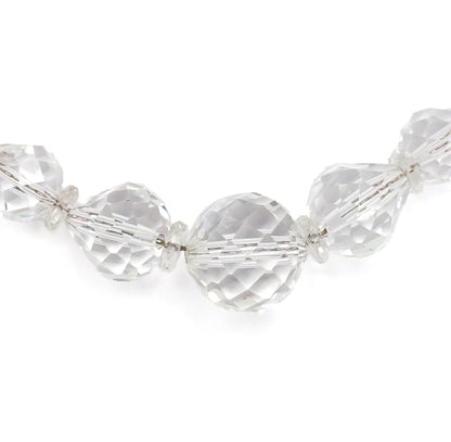 A straight-on view of the necklace's lowest arc, the big round centre bead flanked by flattened and cone-shaped faceted beads with tiny disc spacers between, all evenly lit against white.