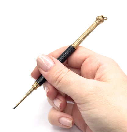 Held between thumb and fingers like a pen, shown on the hand so its small size is clear, with the extended gold filled tip and lead point angled down to the left.