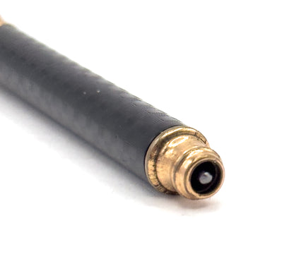 Close view of the barrel running to the lower right, where the black chased rubber meets a ridged gold filled end collar with the telescoping tip drawn in, leaving a dark round opening.