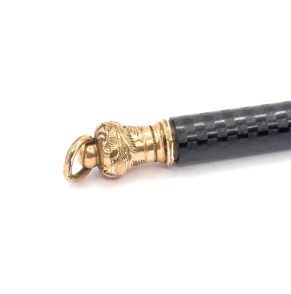 Close crop of the scroll-engraved gold filled cap at the barrel's end, with its oval jump ring swinging to the left and the black chased rubber body receding to the upper right.