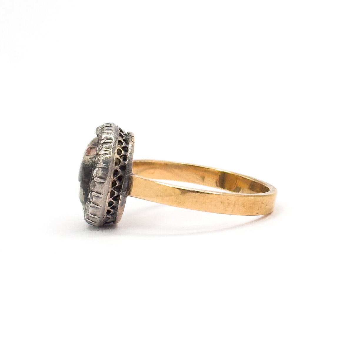 Strict side profile on white, the raised silver bezel edge seen edge-on with its fluted rim and pierced lattice gallery in silhouette, the flat yellow gold shank curving away to the right.