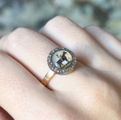 Closer view on the finger, the domed crystal filling the frame so the painted horse and rider and the shifting pale backing read clearly inside the beaded halo of diamonds.