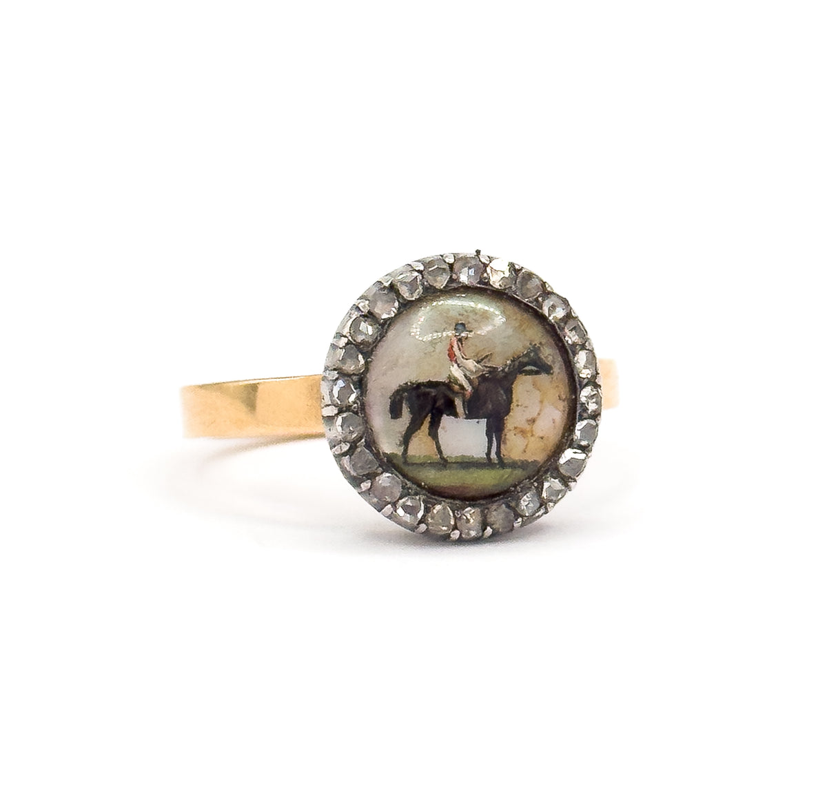 Face-on against a plain white background, off the hand, showing the full round crystal with its painted horse and rider, the complete circle of rose cut diamonds, and the gold shank behind.